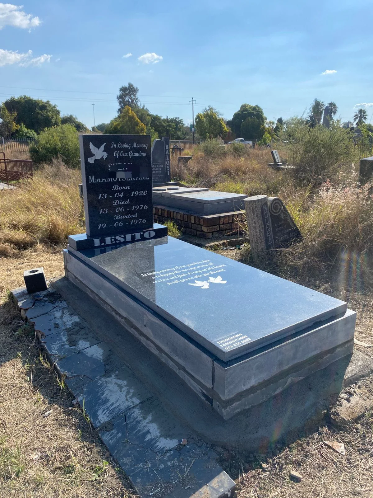 A beautifully crafted double granite memorial headstone in a peaceful garden setting
